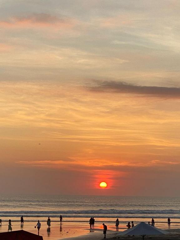 a group of people walking on the beach at sunset at Super Logement in Tangier