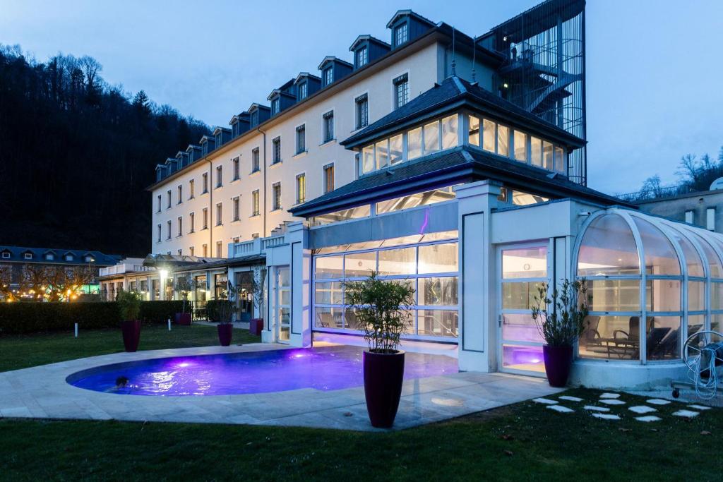 a large building with a pool in front of it at Grand Hôtel & Spa Uriage in Uriage-les-Bains