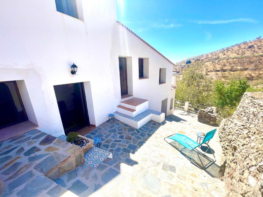 a white house with a chair and a staircase at Casa Amigos Sorvilan - la Bodega in Sorvilán