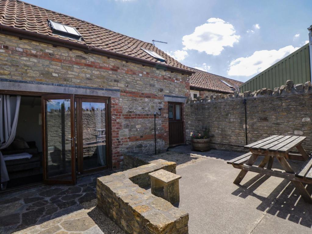 a patio with a wooden bench and a picnic table at Barn Cottage with pre booked use of Indoor Swimming Pool in Frome