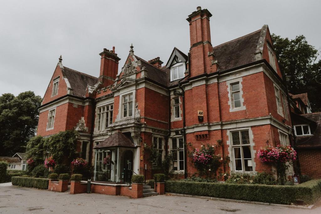 an old red brick building with flowers in front of it at The Coed-Y-Mwstwr Hotel in Bridgend