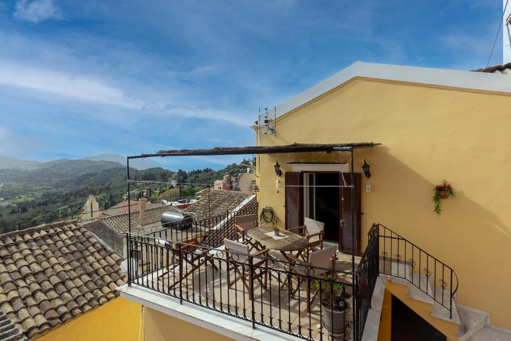 a balcony of a yellow building with chairs on it at Avgi's House Pelekas in Pelekas