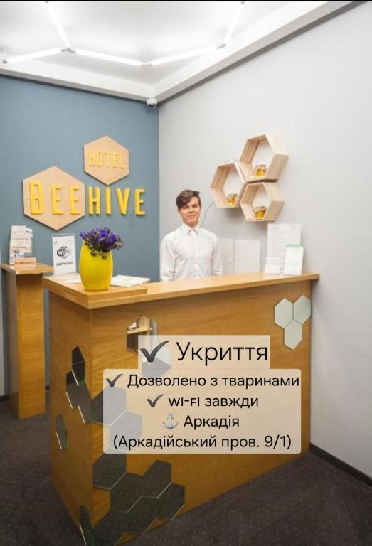 un uomo in piedi dietro una scrivania in un ufficio di Beehive Hotel a Odessa