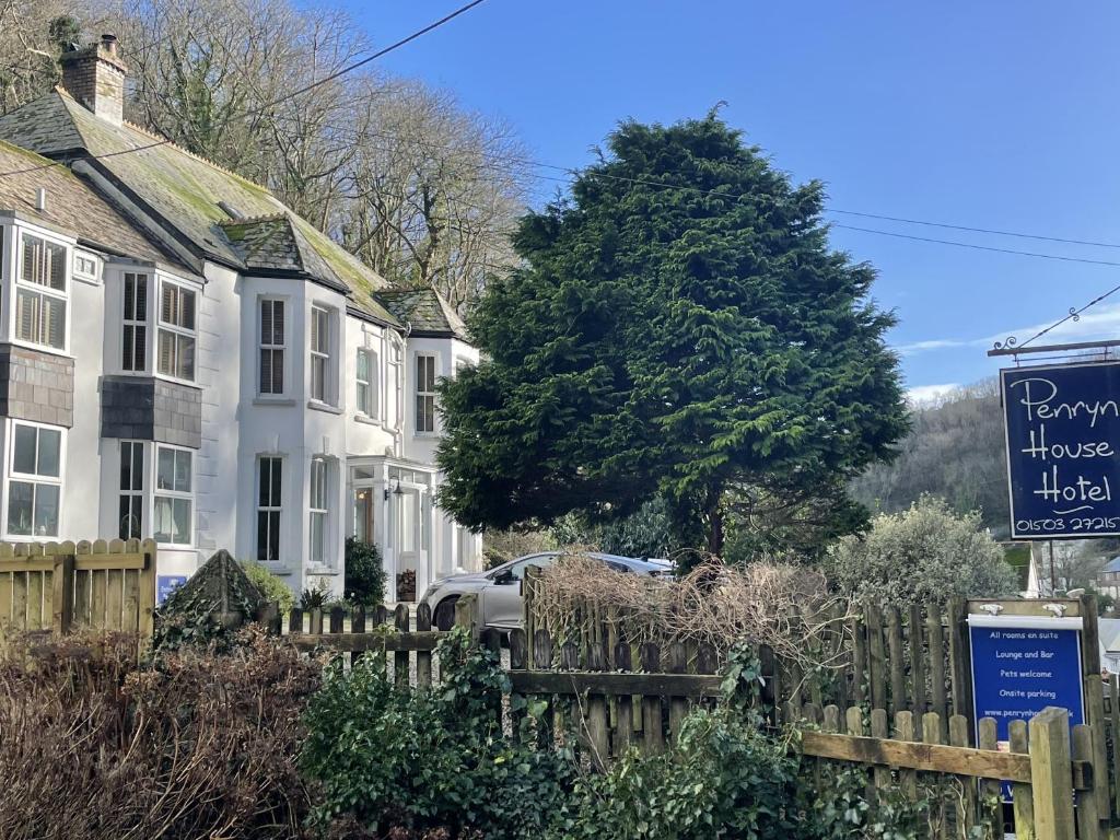 a sign in front of houses and a tree at Penryn House Hotel in Polperro