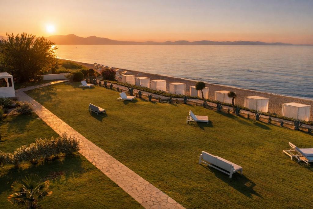 a row of lawn chairs on the beach at sunset at Mareggio Exclusive Residences & Suites in Gythio