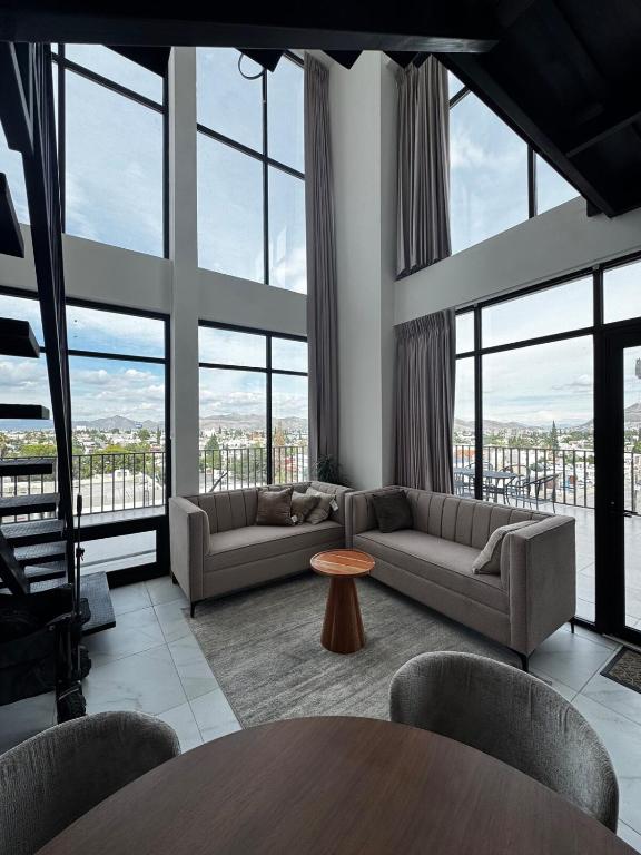a living room with couches and a table and windows at Penthouse Panoramic Terrace, San Felipe in Chihuahua