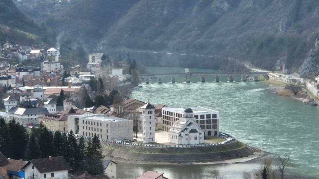 a town on the river with a bridge in the background at Hotel Andrićgrad in Višegrad