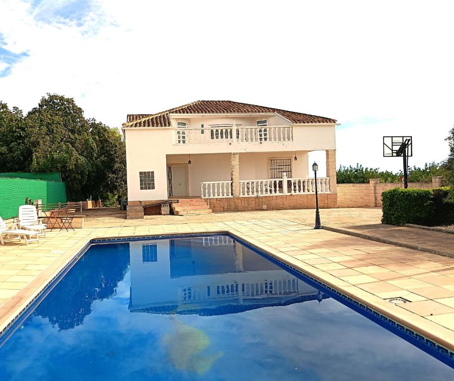 a house with a swimming pool and a basketball hoop at La Villa Blanca in Pedralba