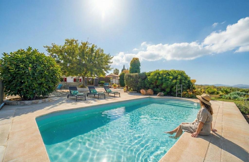 a woman sitting on the edge of a swimming pool at Ideal Property Mallorca - Ca Na Venta in Lloret de Vistalegre