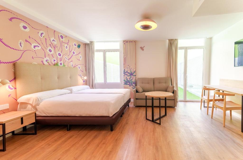 a bedroom with a bed and a chair and a table at Spirit Apartamentos Valladolid Centro in Valladolid