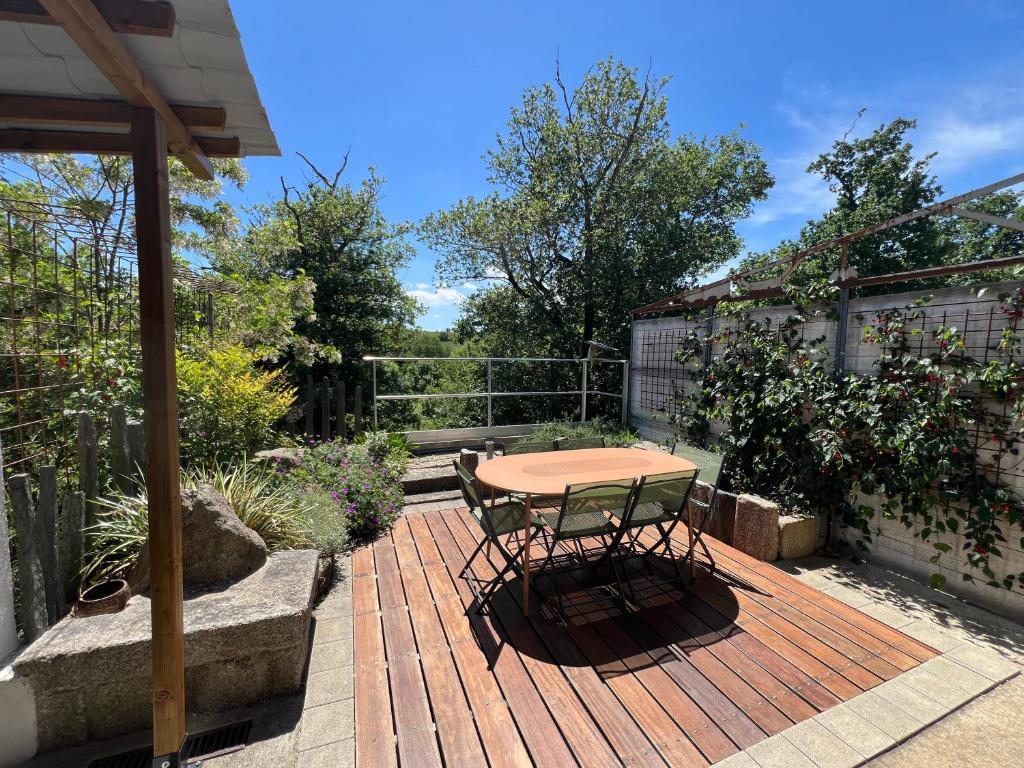 a wooden deck with a table and chairs on it at Les Iris - Maison chaleureuse in Montigné-sur-Moine