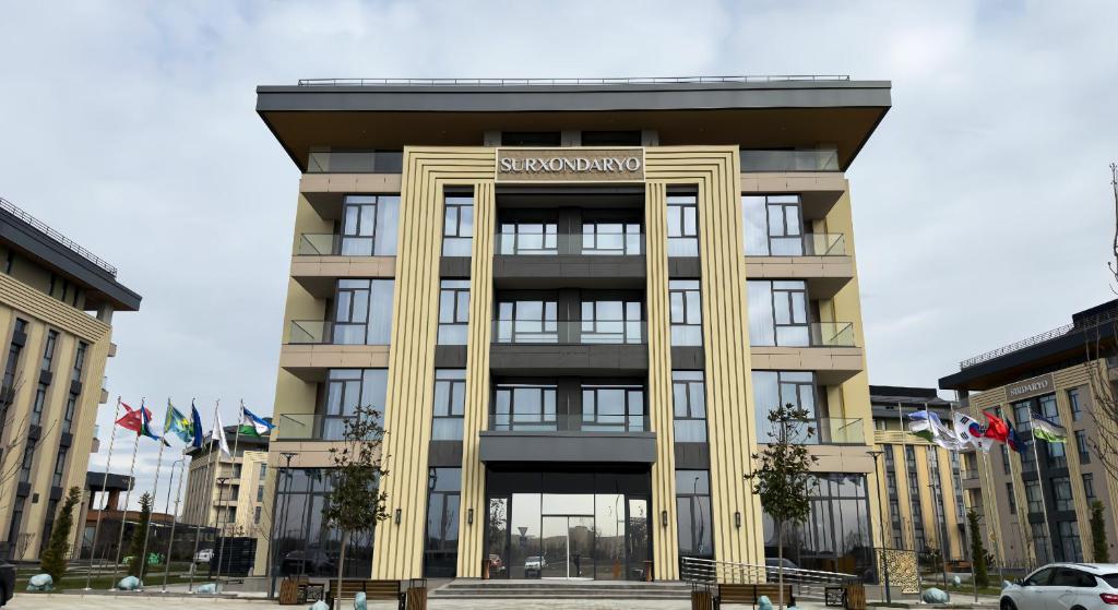 a large building with a sign on the front of it at Surxondaryo Hotel Tashkent in Teshabayguzar
