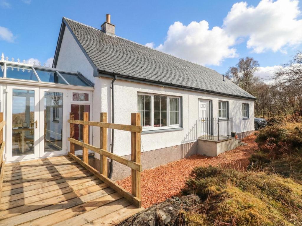 a white cottage with a wooden deck in front of it at Doire An Daimh in Acharacle