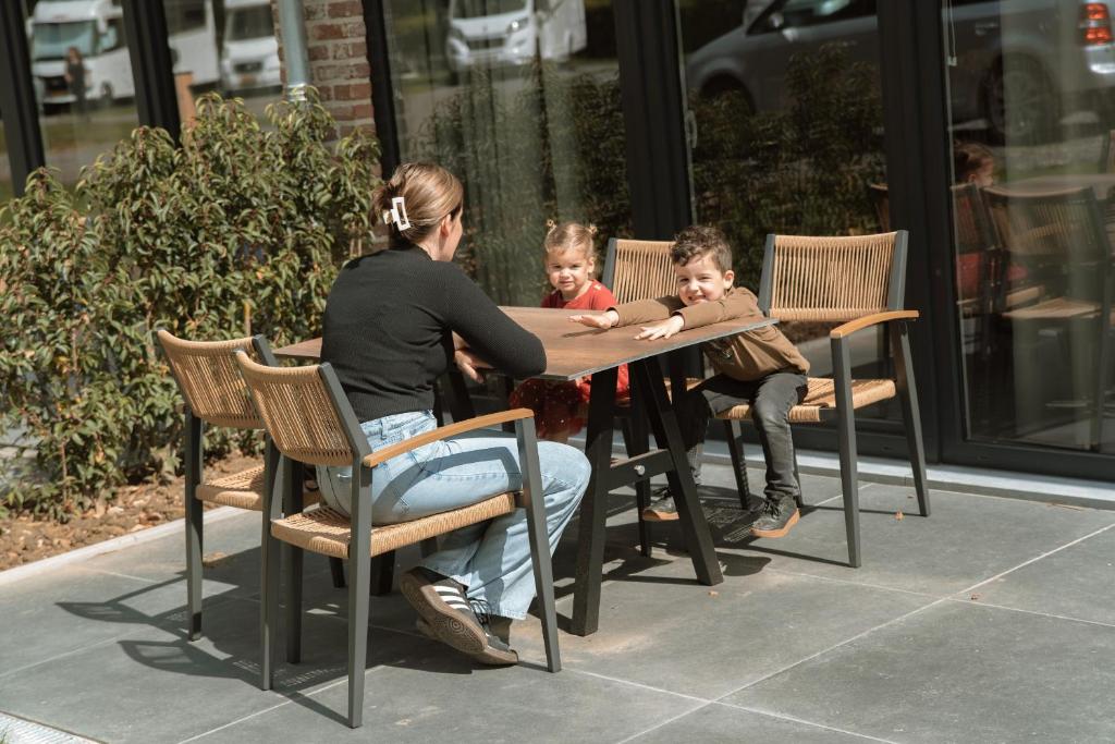 a woman sitting at a table with two children at Camping Natuurlijk Limburg - Studio 1 in Voeren