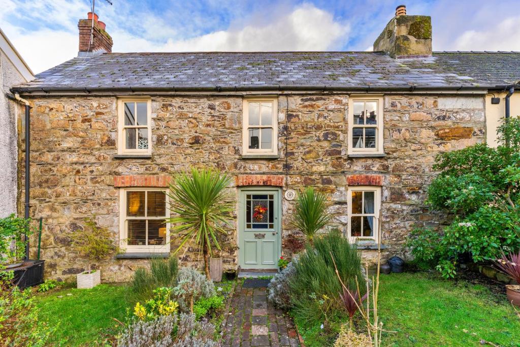an old stone house with a green door at Finest Retreats - Wallis Cottage in Fishguard