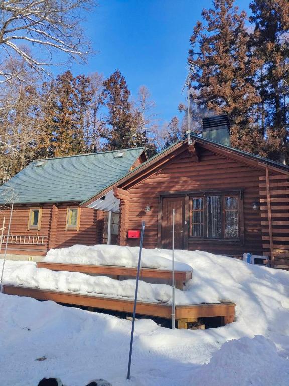a log cabin with snow in front of it at LOG-INN Hakuba in Hakuba