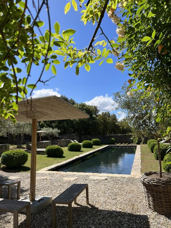 a swimming pool with an umbrella and two chairs next to it at Le Mas de Béthel in Gordes
