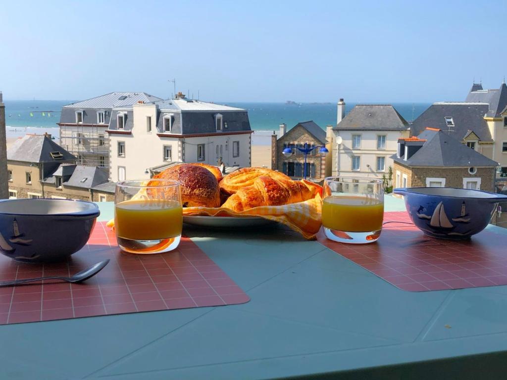 a table with two glasses of orange juice and bread at Le Balcon de la Conchée in Saint Malo