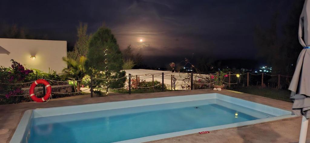 a blue swimming pool in a yard at night at Villa Ti Zil in Rodrigues Island