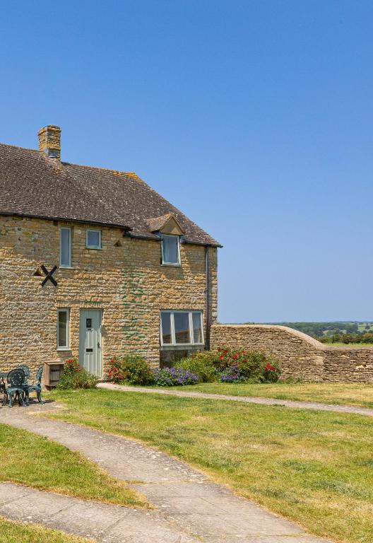 a stone house with a bench in front of it at Knapp Cottage in Charlbury