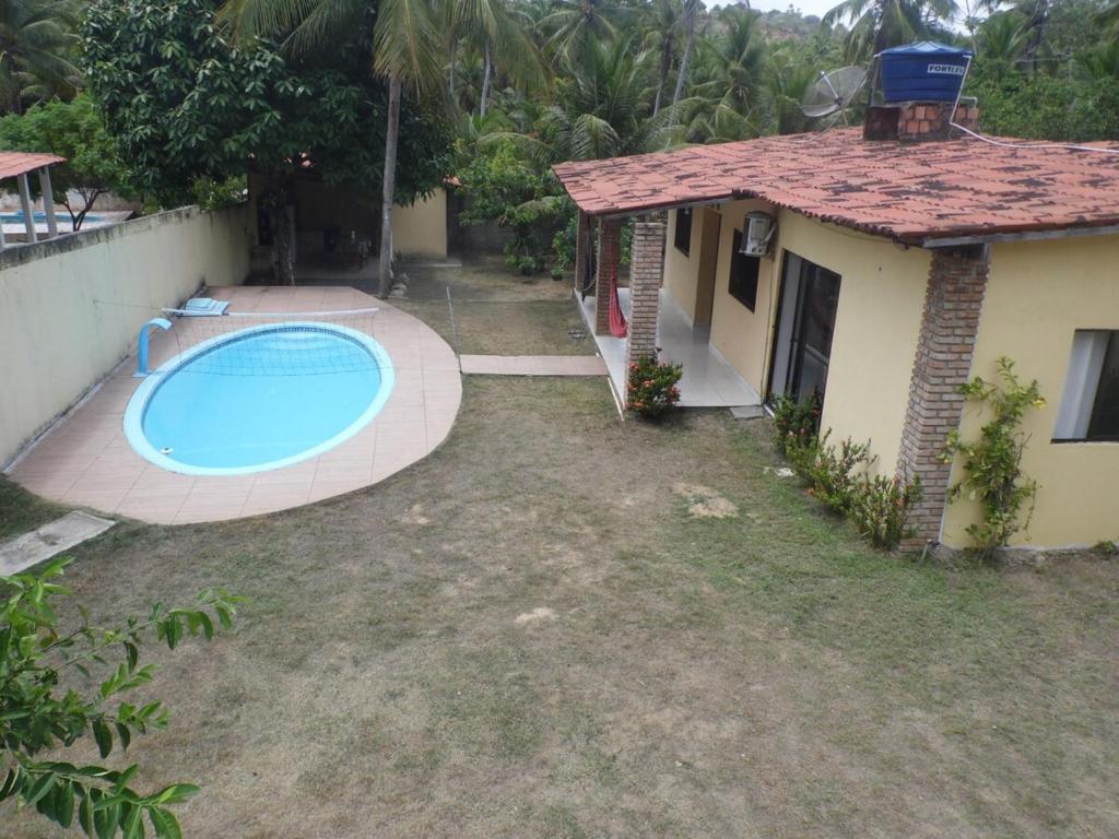 ein Hinterhof mit Swimmingpool neben einem Haus in der Unterkunft Bitingui infinity in Japaratinga