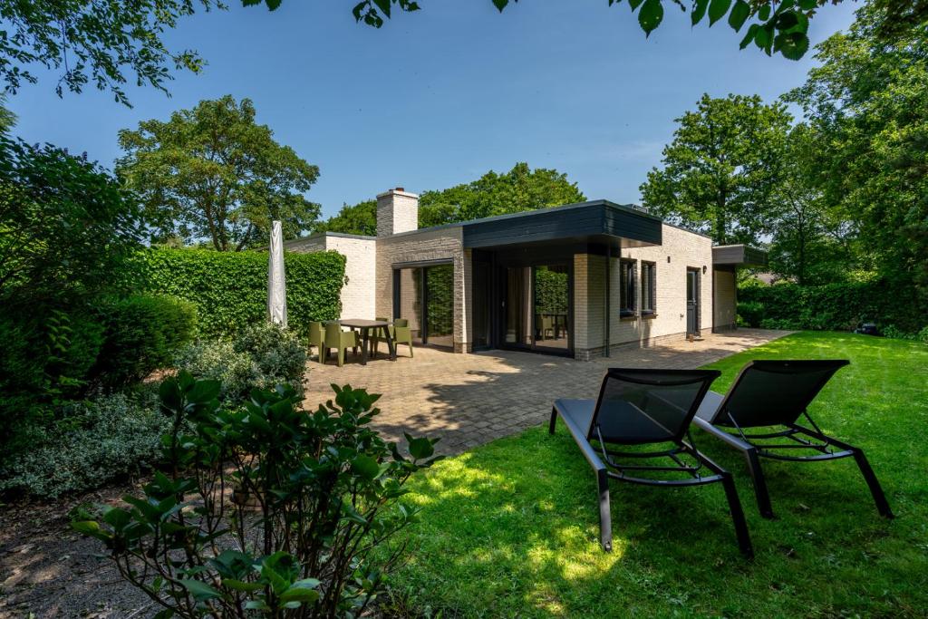 a house with two chairs in the yard at Zeebries in De Koog