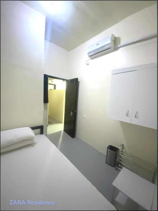 a white room with a bed and a door to a hallway at Zara Residence Room1 in Lagao