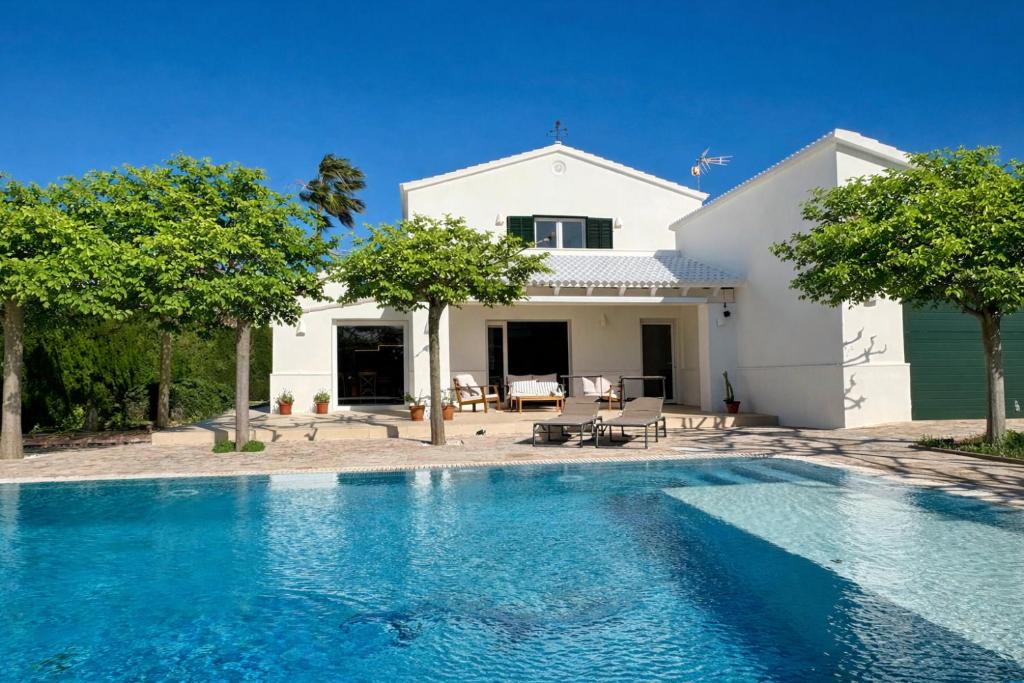 a villa with a swimming pool in front of a house at Bella Mar in Son Carrio