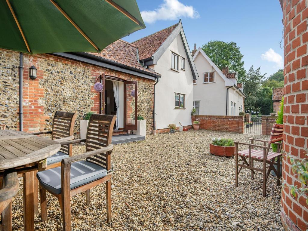 a patio at a house with chairs and an umbrella at Pear Tree Cottage in Banham