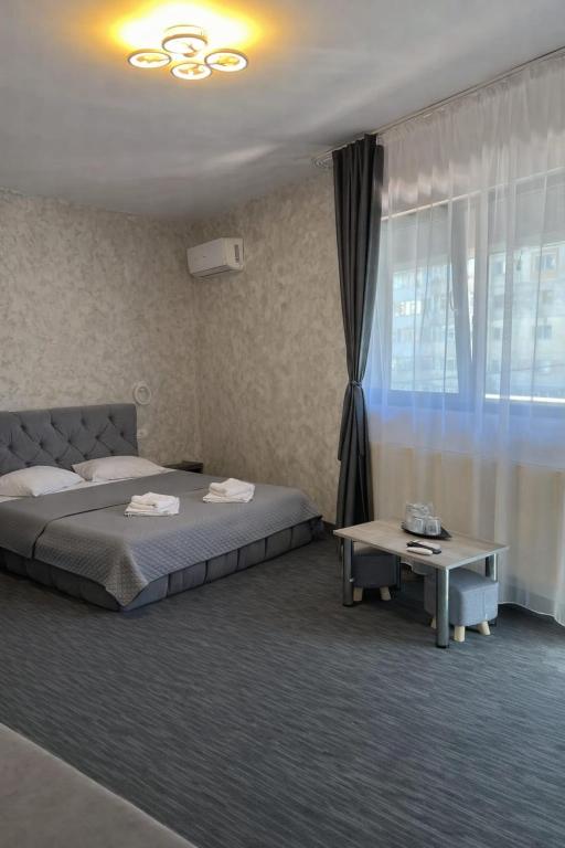 a bedroom with a bed and a table and a window at Hotel AmA in Constanţa