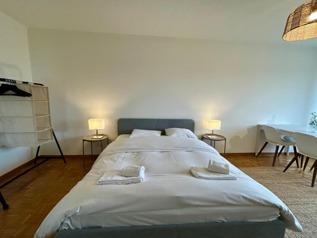 a large white bed in a room with two lamps at Cozy Studio in Witikon District in Zurich