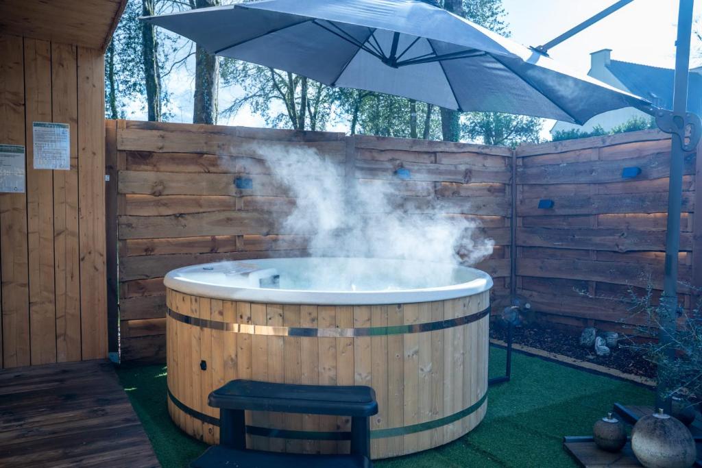 a hot tub with smoke coming out of it with an umbrella at Gîte de charme Ò Chalet in Camors
