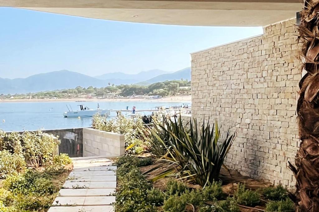 a brick wall next to a beach with a boat in the water at Rare T2 New, Waterfront in Porticcio