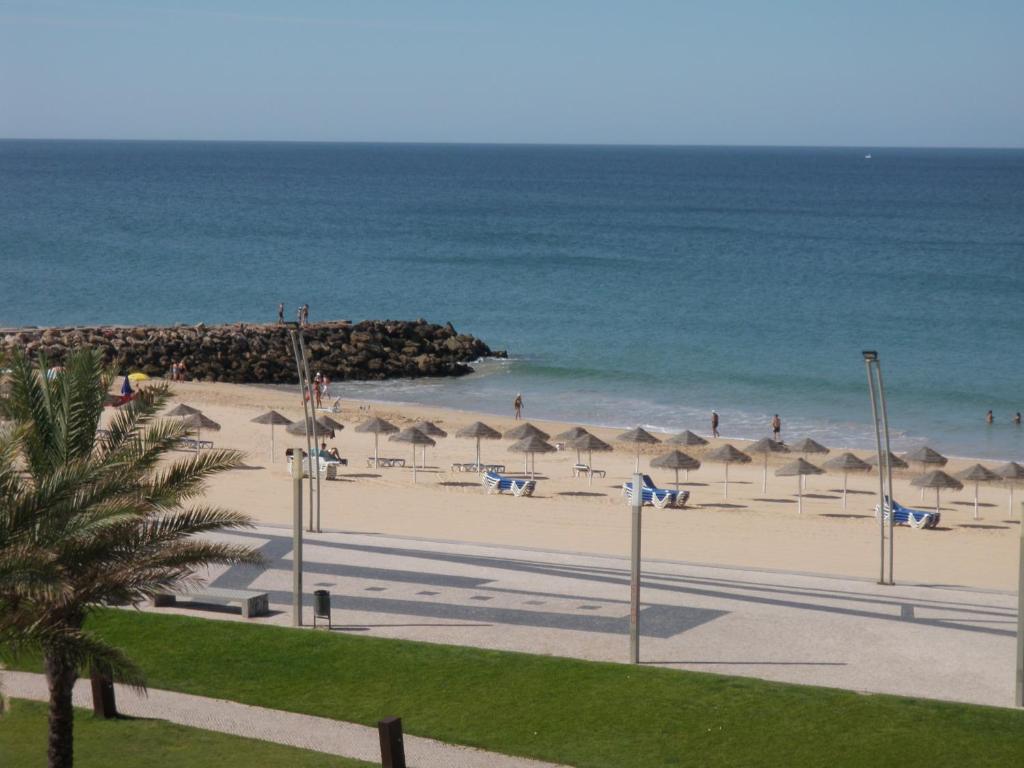 a beach with umbrellas and people on the beach at Mare Viva Beach Apartment in Quarteira