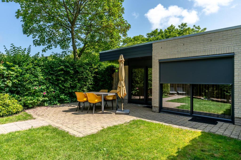 a patio with a table and chairs and an umbrella at Zilte Bries in De Koog