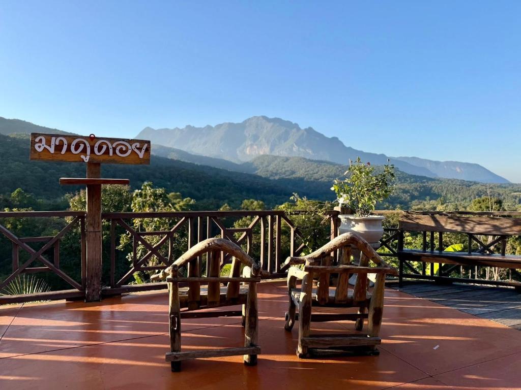 two chairs on a deck with mountains in the background at มาดูดอย - Madoodoi in Ban Mae Na