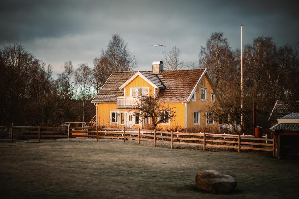 a yellow house with a fence in front of it at Gårdshuset på Wrågården in Falköping
