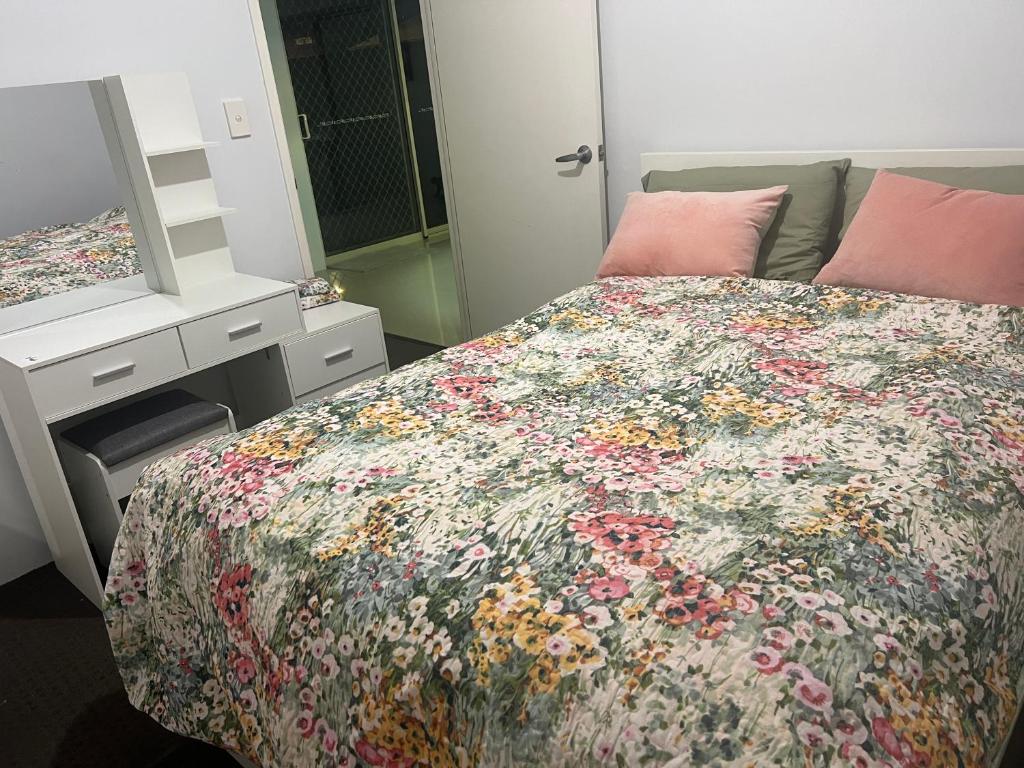 a bedroom with a bed with a floral bedspread at Homy Kwinana in Wellard