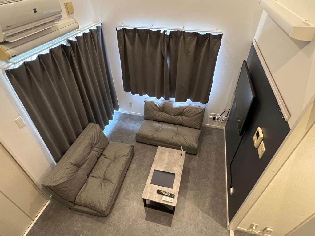a small living room with a couch and a tv at イマココホテル in Yogi