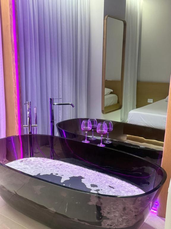 a bathroom with a black tub with wine glasses at Solea Apartment in Vlorë