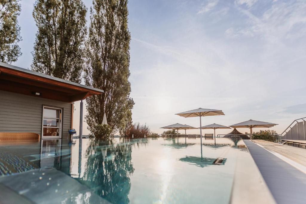 a swimming pool with umbrellas next to a house at Tschermonegg "Wohnen beim Wein" in Sulz