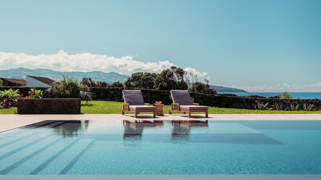 two chairs are sitting next to a swimming pool at Casa do Mar - North Coast Ocean Views in Calhetas