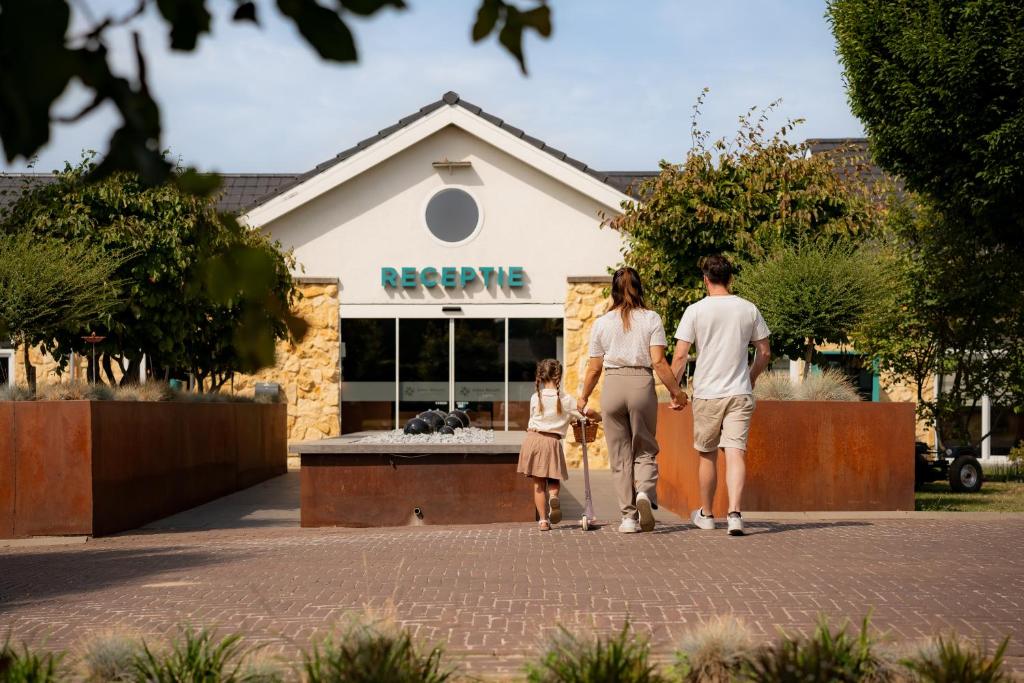 a family walking down a sidewalk in front of a store at Resort Mooi Bemelen in Bemelen