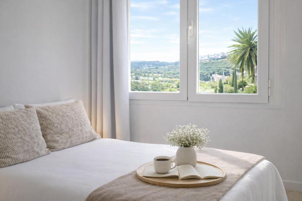 a bed with a tray with two cups and a vase with flowers at Noctua Duquesa Beach 009 in Manilva