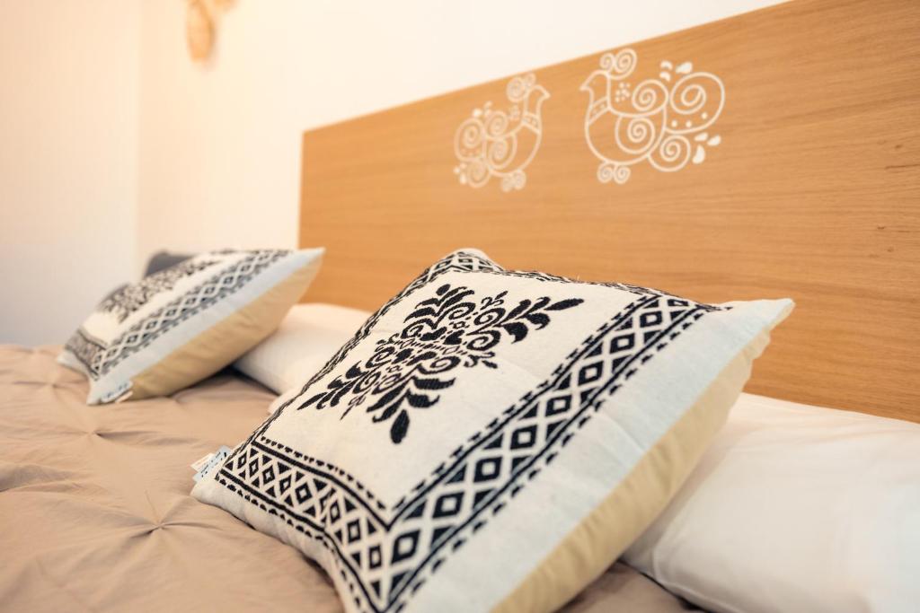 a bed with white pillows and a wooden headboard at Saludu Boutique in Porto Torres