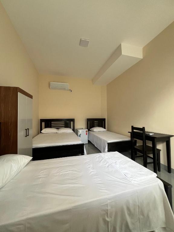 a hotel room with two beds and a desk at Hotel Brilhante 2 in Itacarambi