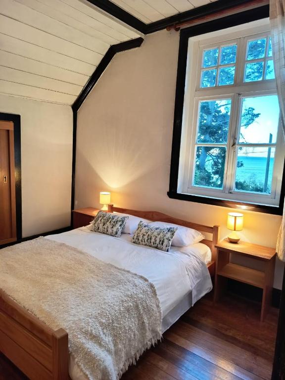 a bedroom with a bed with two pillows and a window at Hostal Los Riscos in Llanquihue