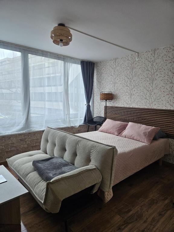 a bedroom with a large bed and a couch at Studio Le Belvédère TURCKHEIM in Turckheim