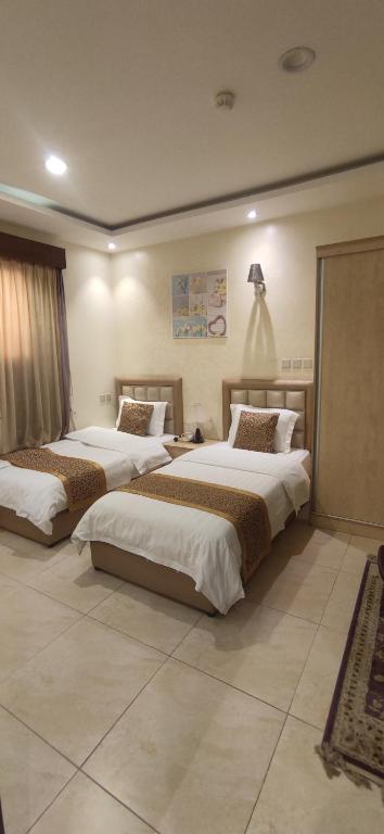 a hotel room with three beds in a room at عمارة النفيسة السكنية in Unayzah