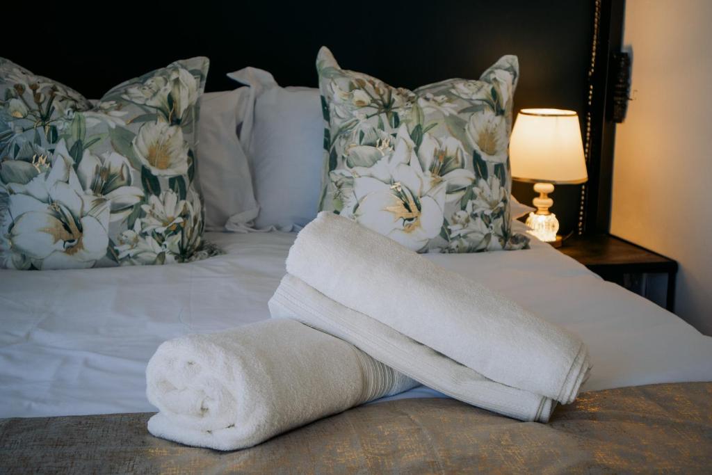 a towel laying on top of a bed with pillows at La Grande in Benoni